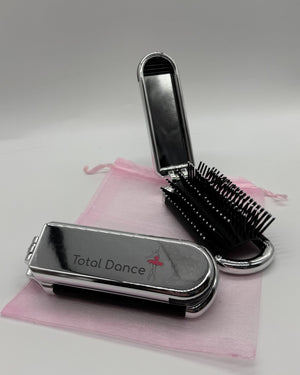 Total Dance foldable hair brush open showing the removable mirror and cushioned bristles beside the folded compact with pink organza pouch