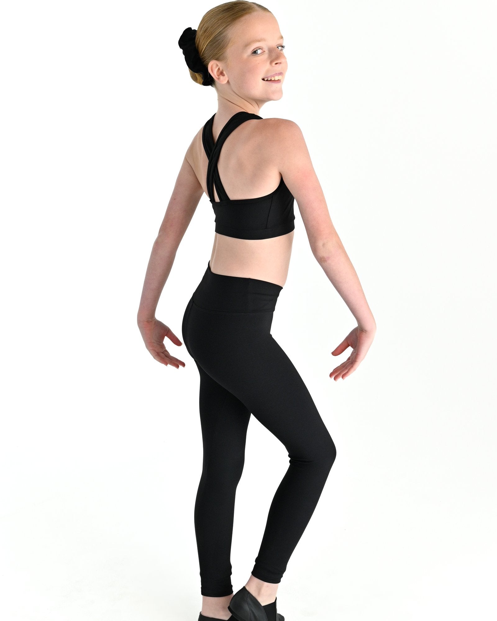 Young dancer wearing the Violet crossed back dance crop top with contrast binding in Black, alternate view